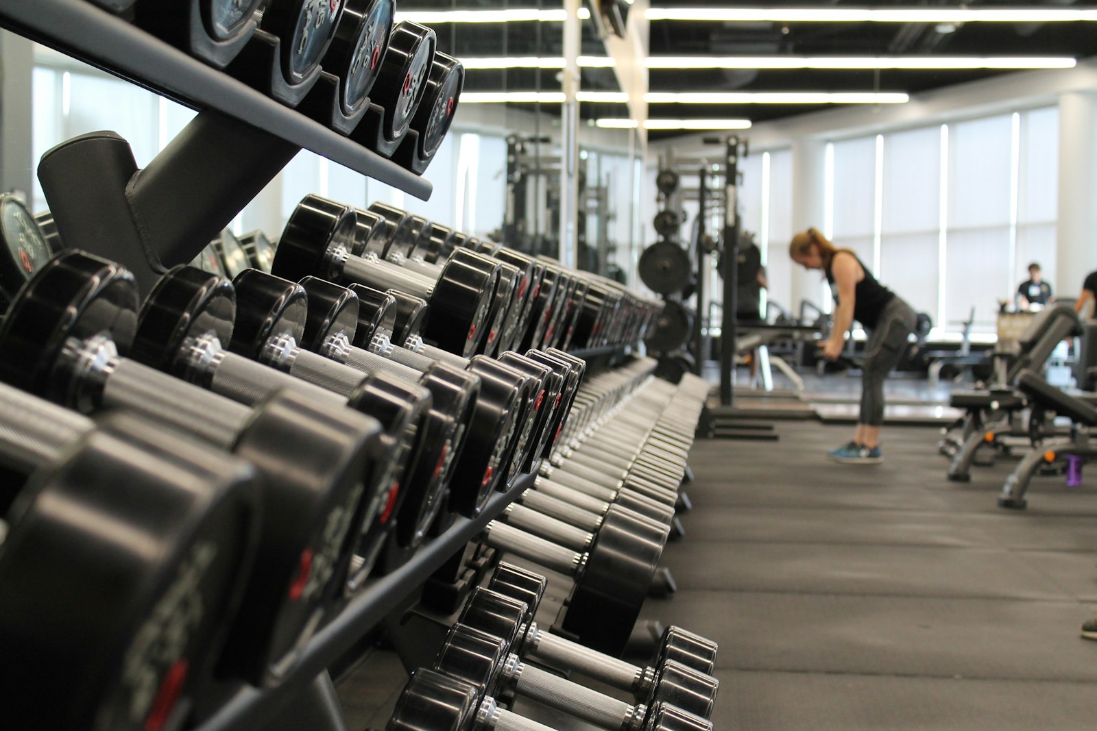 Gym floor with weights and soft-focus people training in the background